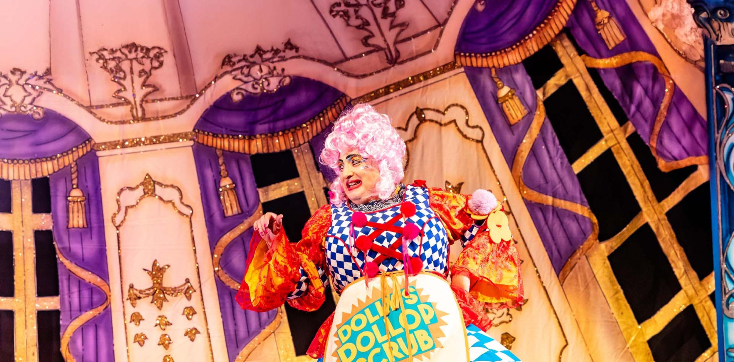 Dame Dolly Duster in panto looking colourful and smiley.