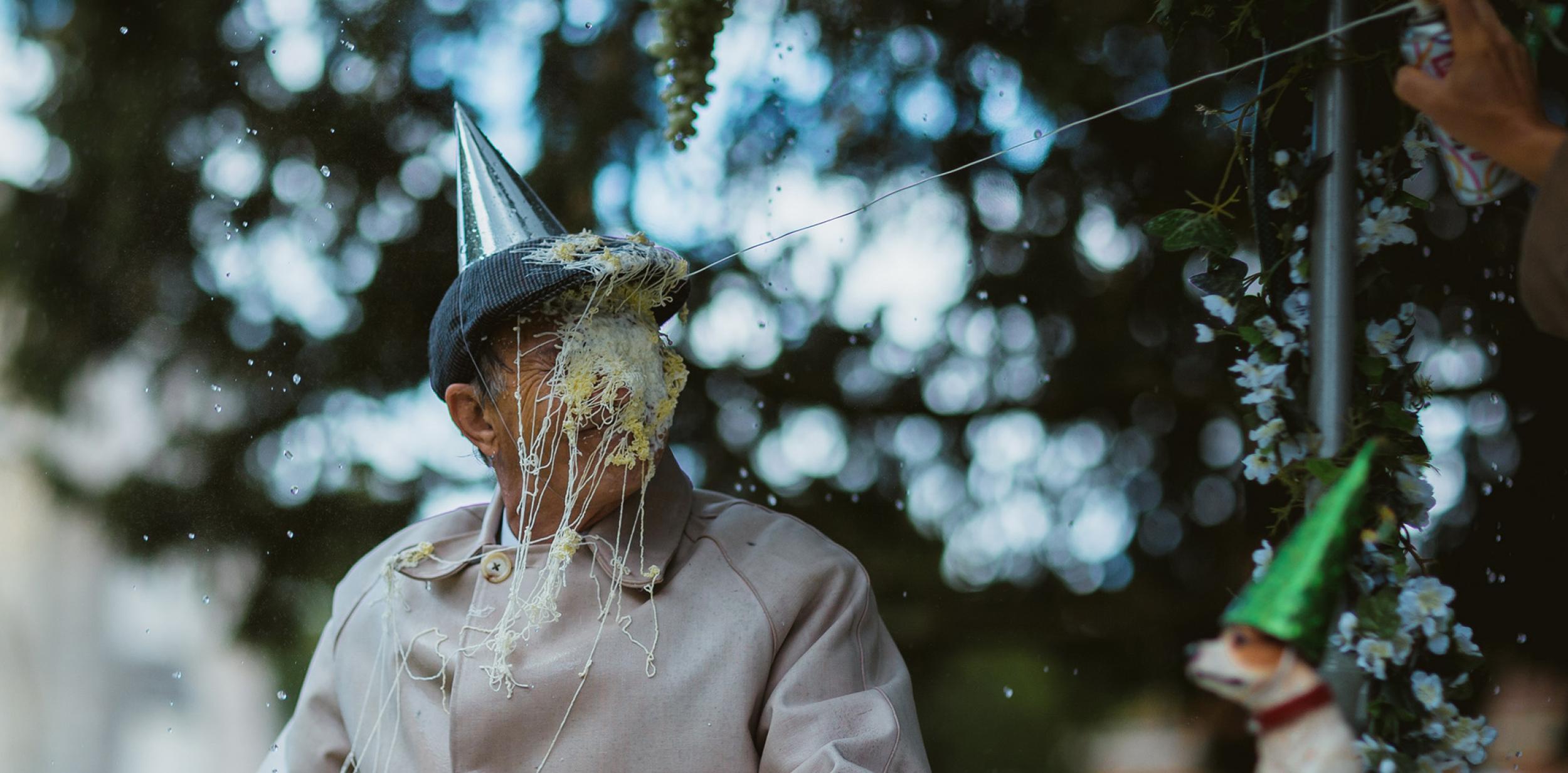 Man wearing party hat with face covered in silly string