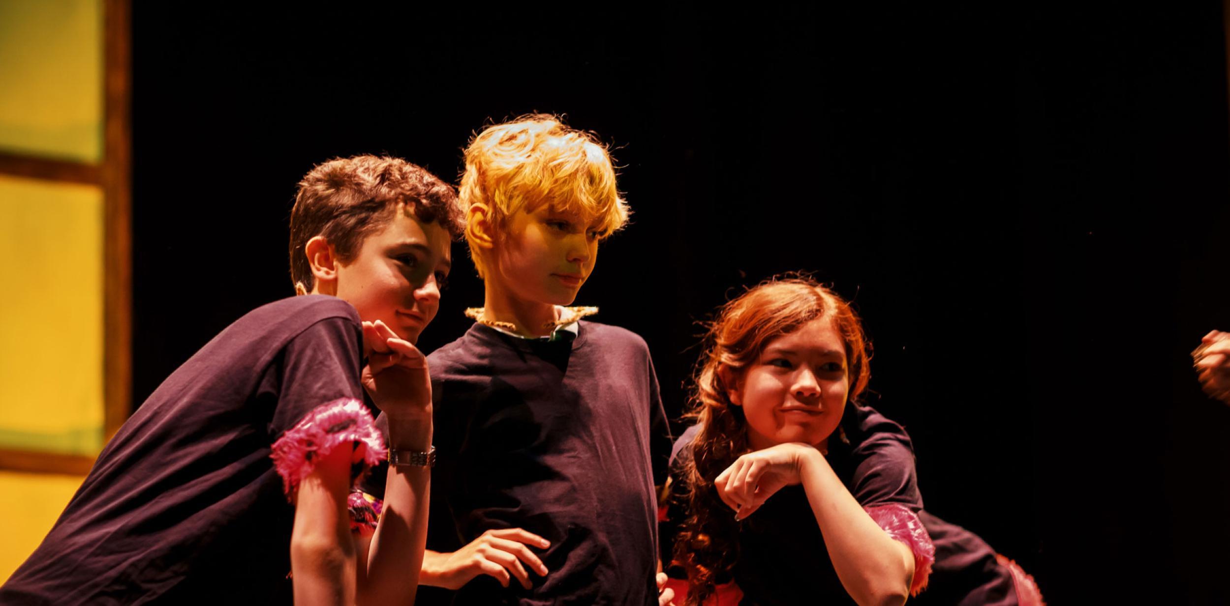 Three young children performing on stage