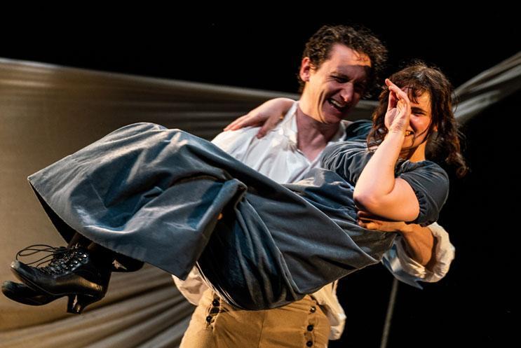 Two people in period costume, smiling and laughing