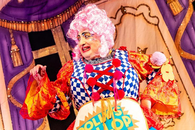 Dame Dolly Duster in panto looking colourful and smiley.