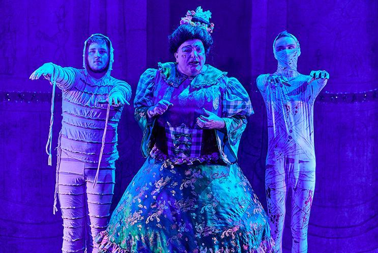 Panto Dame singing between two young performers dressed as mummies