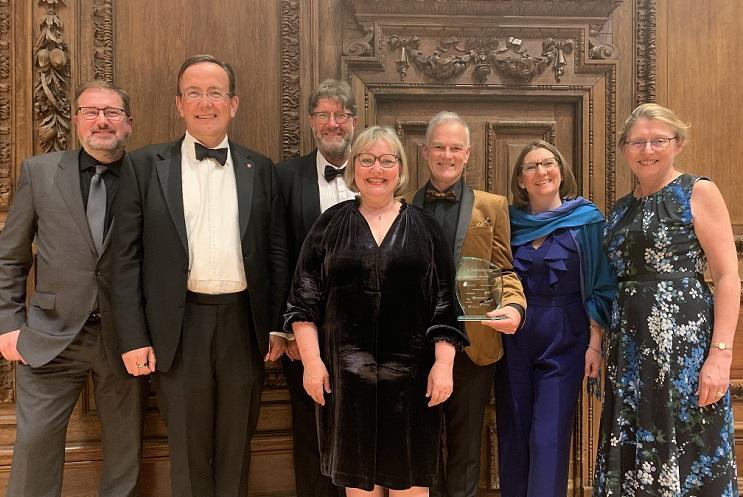 Group of people in black tie holding a glass award