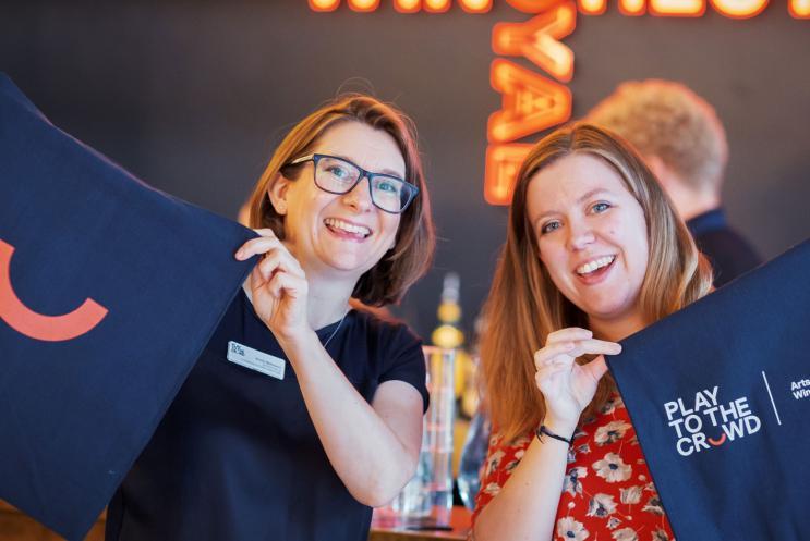 Play to the Crowd team members holding branded bags