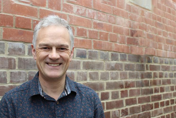 Deryck Newland standing in front of a brick wall.