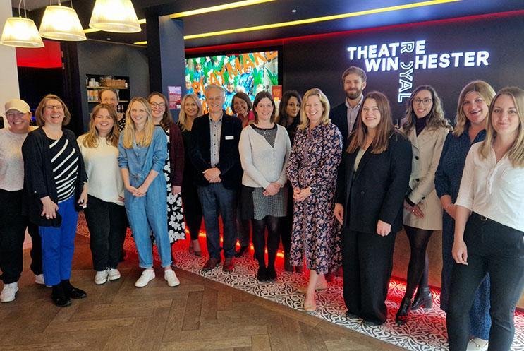 A group of people stood in front of a bar with Theatre Royal Winchester logo behind