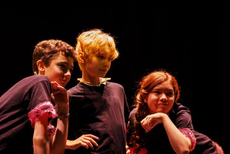 Three young children performing on stage